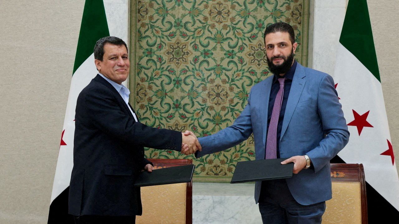 Syria's interim president, Ahmed al-Sharaa, and commander of Syria's Kurdish-led forces, Mazloum Abdi, shake hands after Syria reached a deal to integrate the Kurdish-led Syrian Democratic Forces with state institutions, the Syrian presidency said on Monday, in Damascus, Syria, in this handout released on March 10. (SANA/Handout via REUTERS)