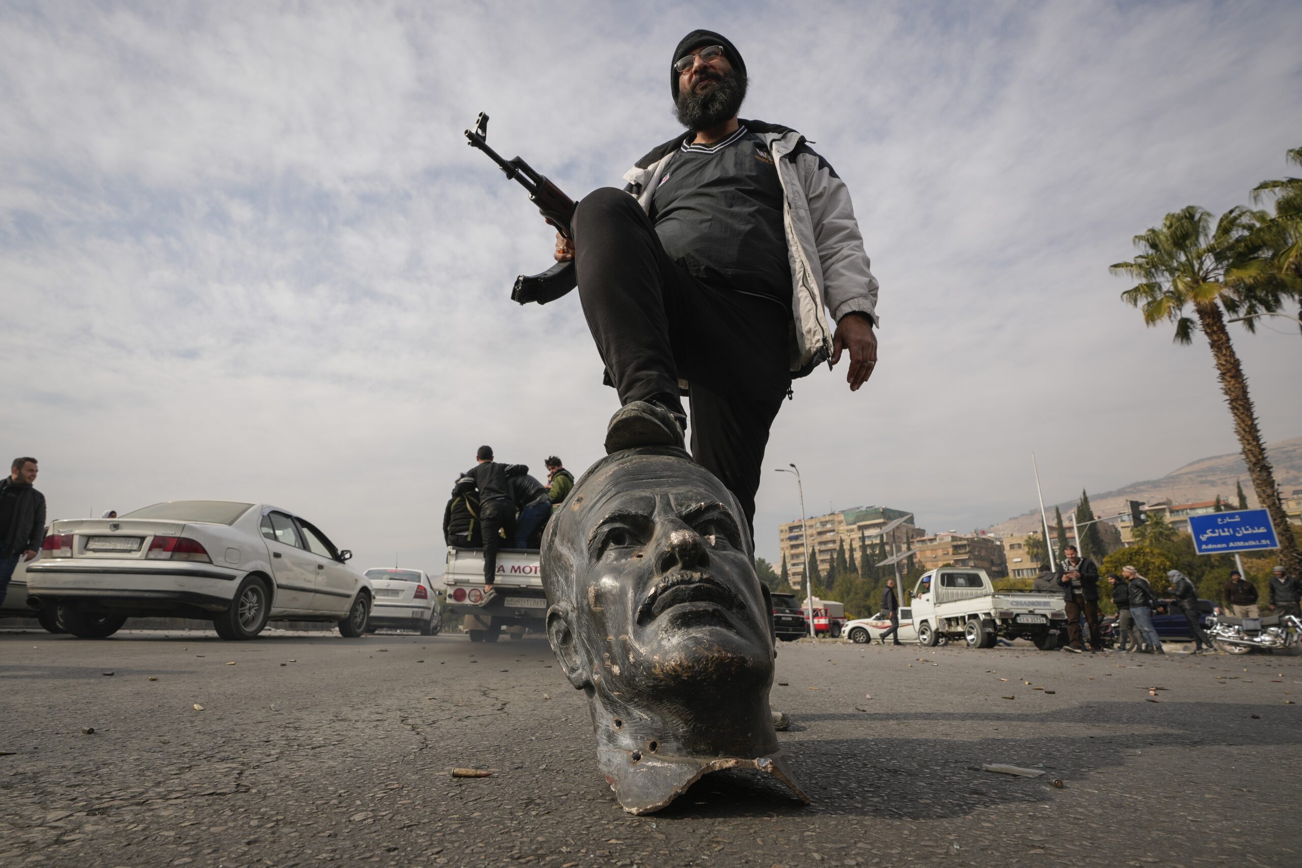 An opposition fighter steps on a broken bust of the late Syrian President Hafez al-Assad in Damascus, Syria, December 8. (AP Photo/Hussein Malla)
