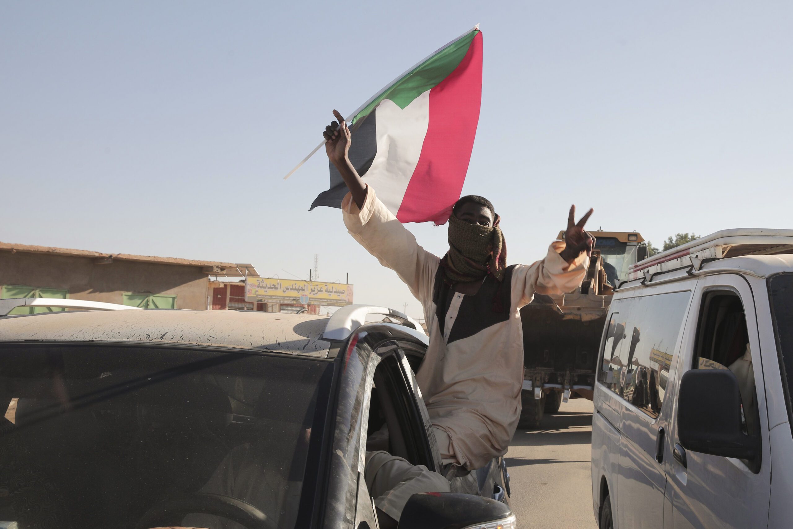 A Sudanese man gestures waving a Sudan flag in Merowe, Sudan, January 11. (AP Photo/Marwan Ali)