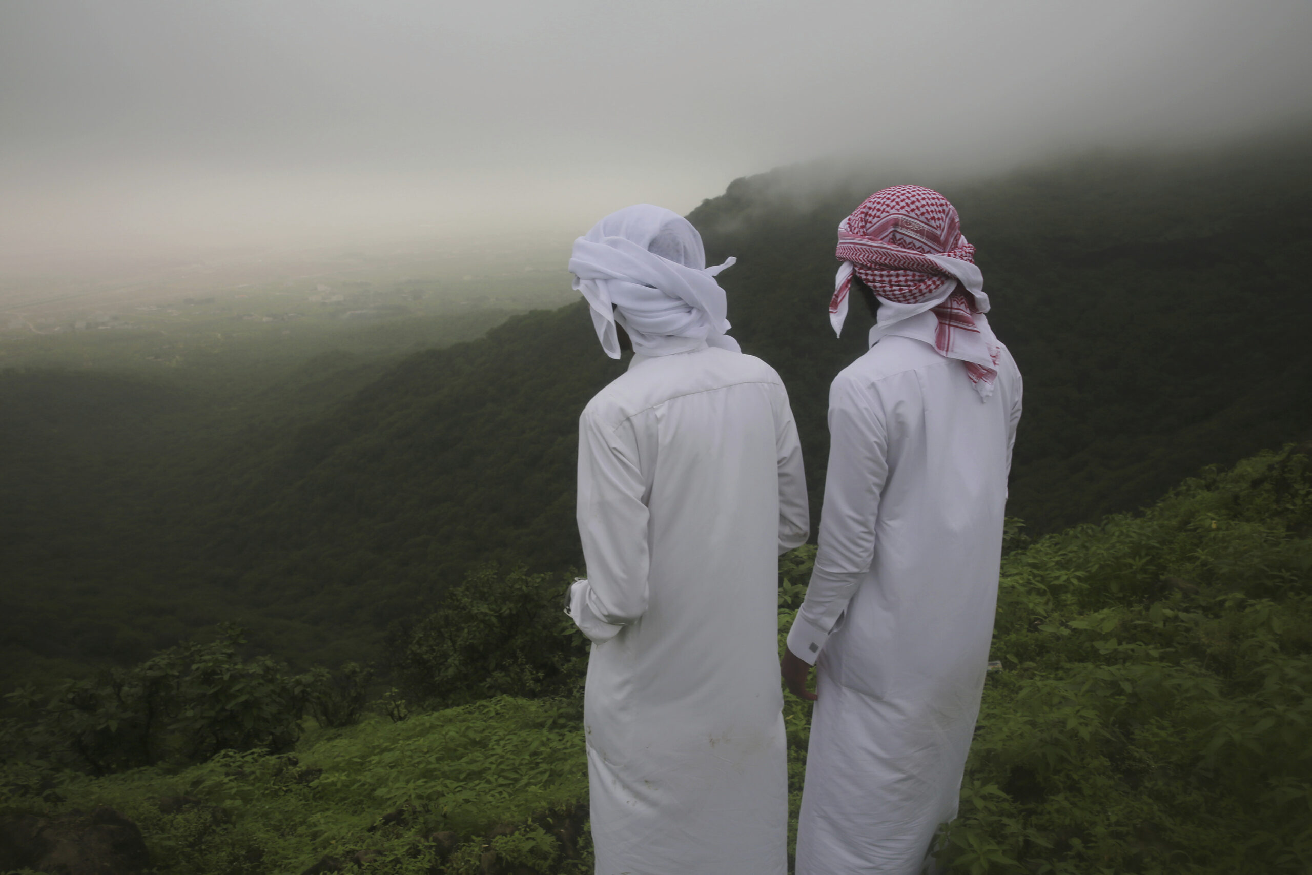 Two teenagers peer out off a cliff in the fog-covered Jabal Ayoub mountains north of Salalah in southern Oman during the annual summer monsoon, August 2, 2017. (AP Photo/Sam McNeil)