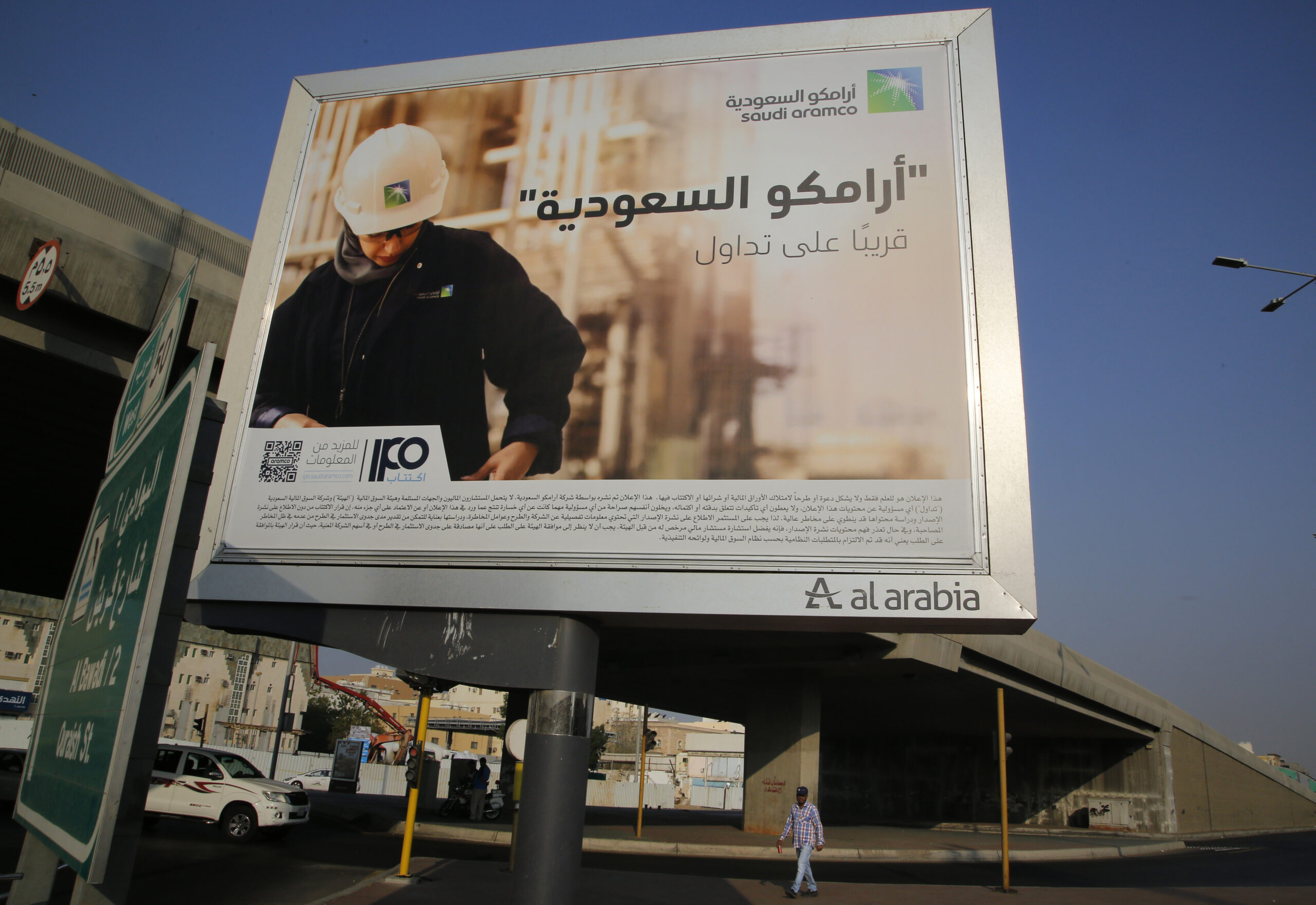 A man walks under a billboard displaying an advertisement for Saudi Aramco, reading: "Saudi Aramco, soon on stock exchange," Jeddah, Saudi Arabia, Nov. 12. (AP Photo/Amr Nabil)