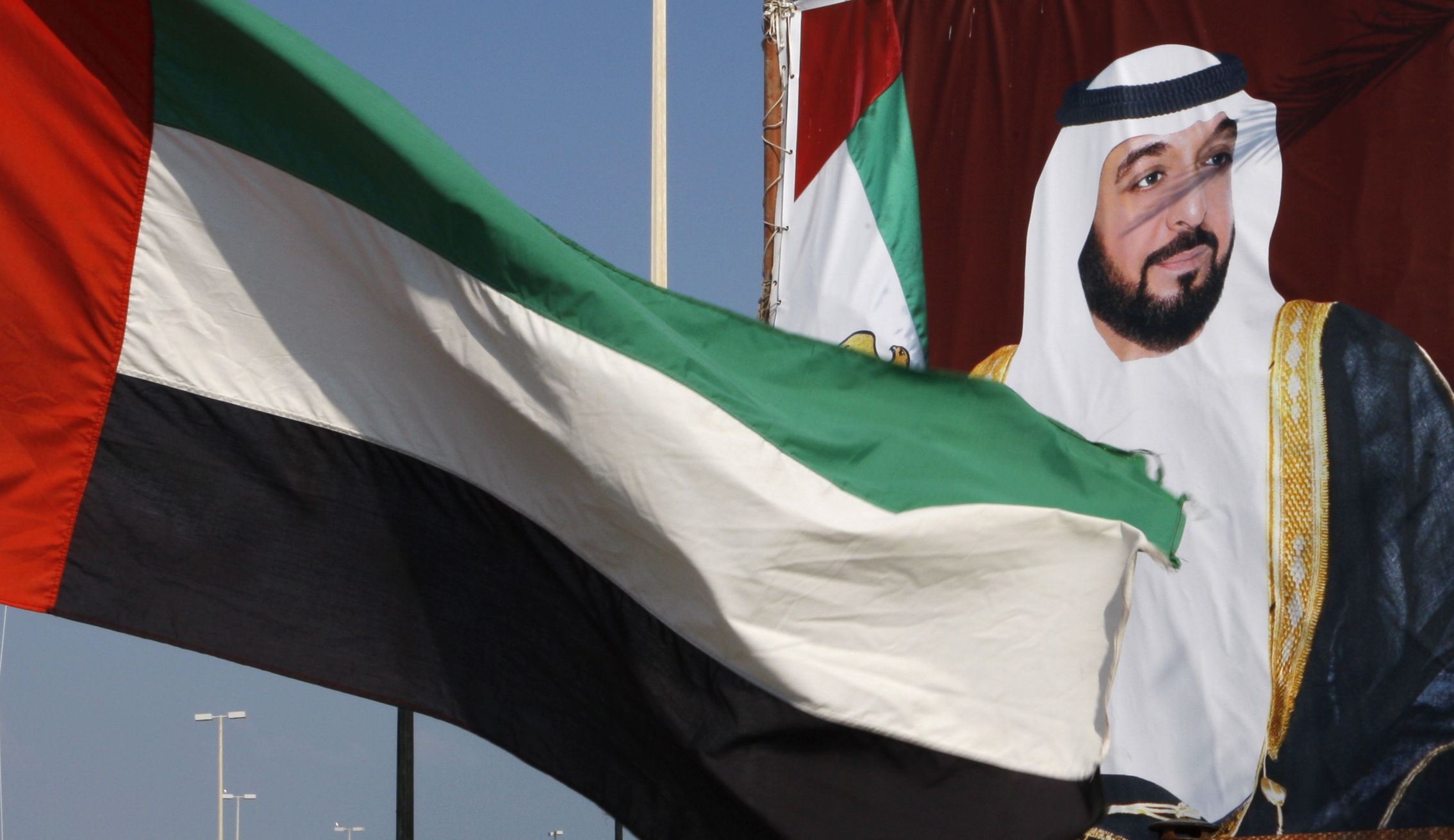A UAE flag waves in front of a poster of President Sheikh Khalifa bin Zayed al-Nahyan in Abu Dhabi, United Arab Emirates, Dec. 15, 2009. (REUTERS/Ahmed Jadallah)
